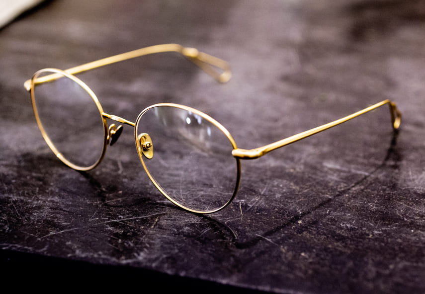 Nahaufnahme Brille mit dünner Metallfassung auf dem dunklen Stein, Marke Ahlem.